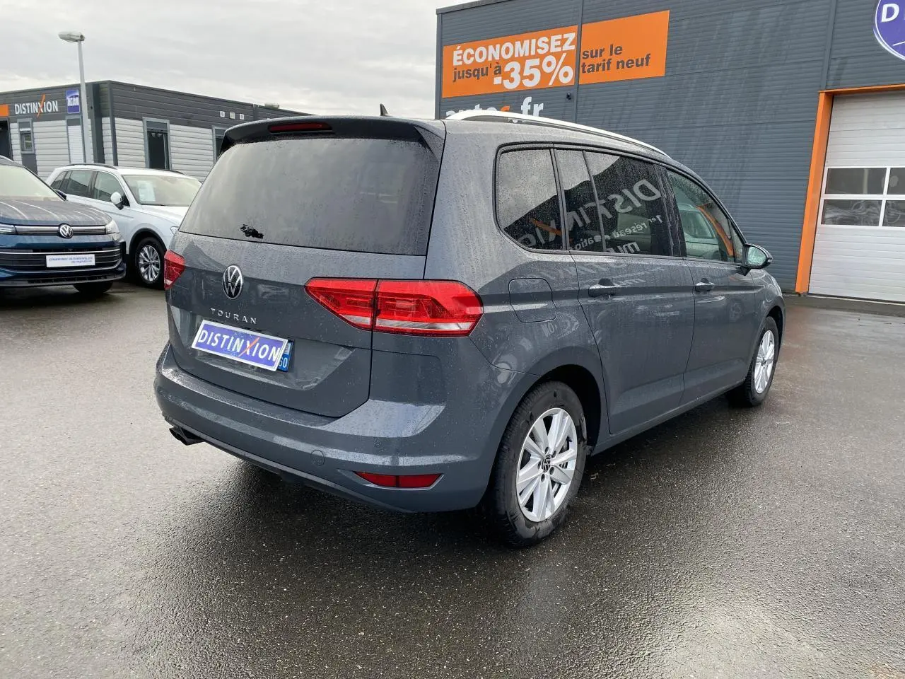 Vue 3/4 arrière droite d'un Volkswagen Touran gris dauphin avec vitres surteintées et jantes alliage 16 pouces.