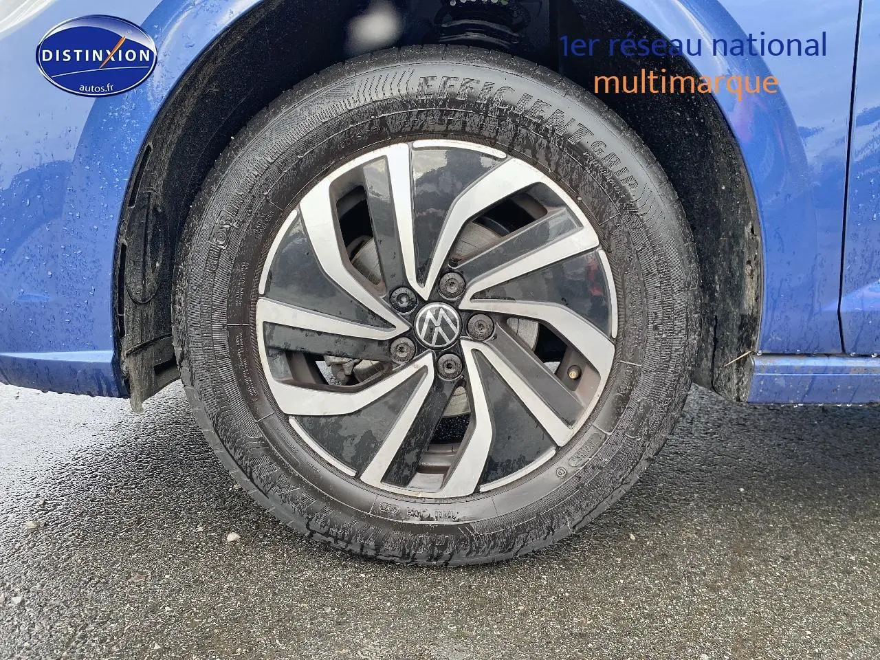 Gros plan sur la roue avant gauche avec jante alliage bicolore, carrosserie bleu récif visible en arrière-plan.