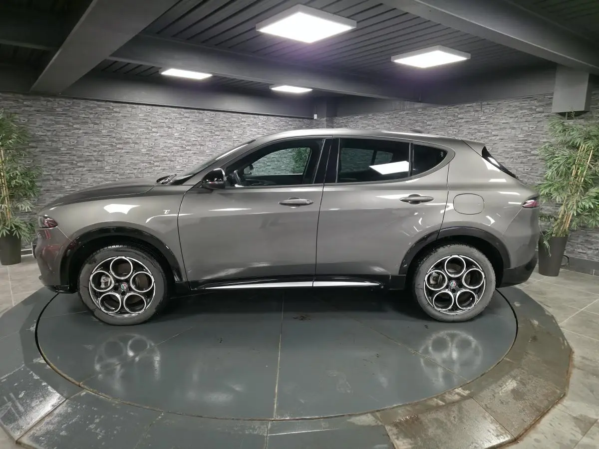Vue de profil côté gauche de l'Alfa Romeo Tonale gris métallisé avec jantes alliage 18 pouces en showroom.