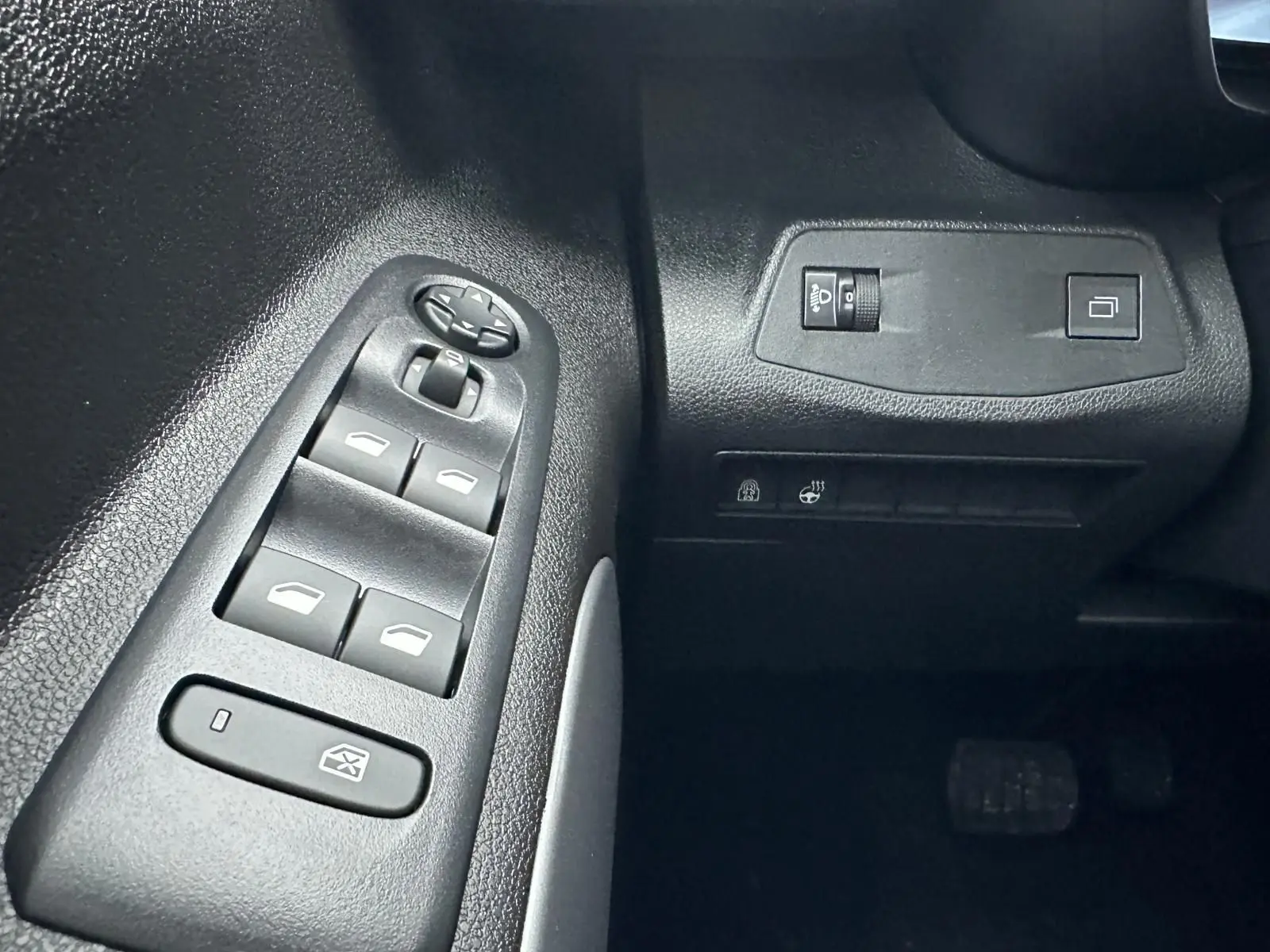 Gros plan sur les commandes de lève-vitres et réglages côté gauche du tableau de bord du Citroën Berlingo gris Artense.