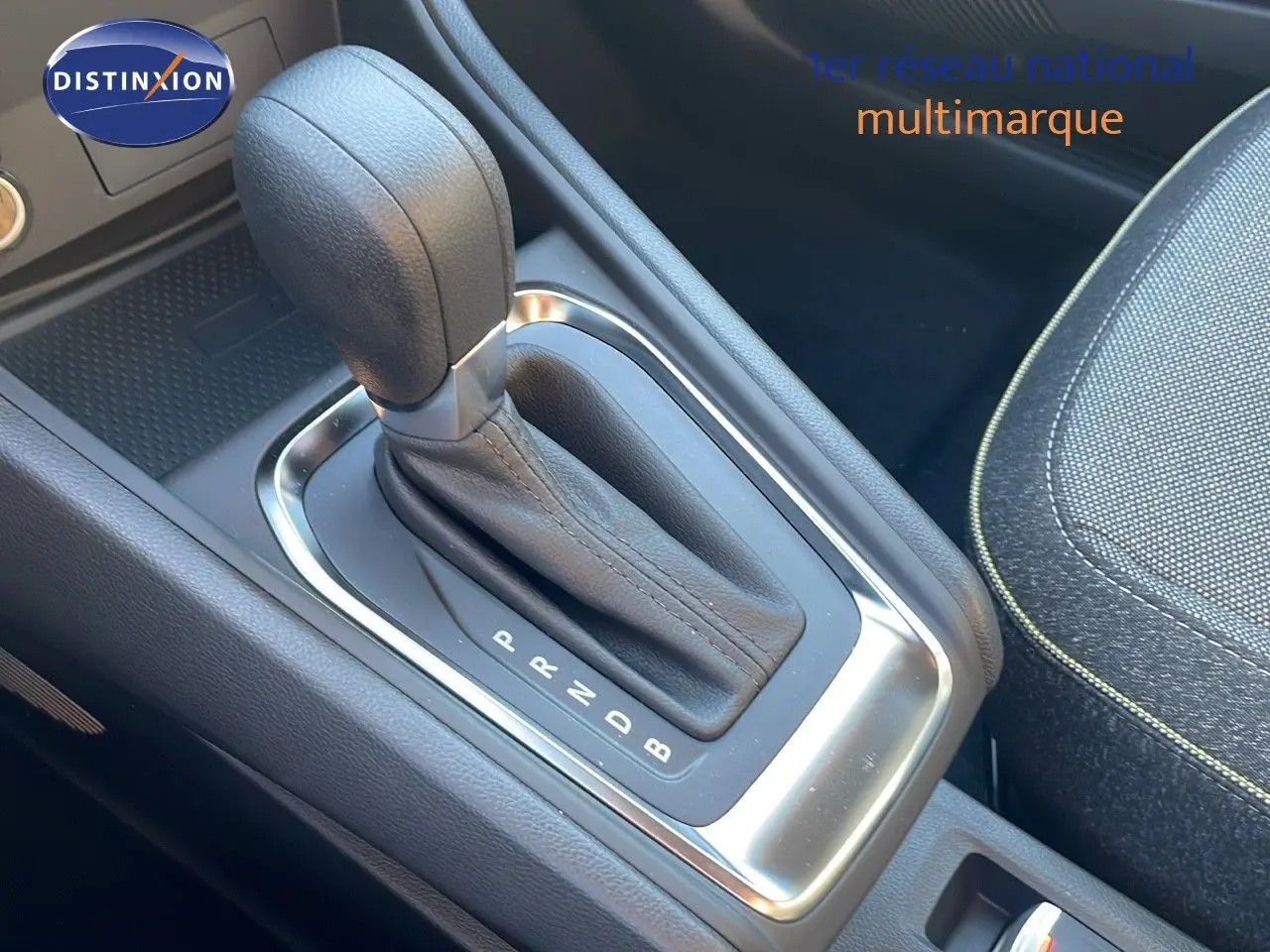 Le levier de vitesse automatique en cuir noir du Renault Captur E-Tech hybride, avec console centrale et siège tissu gris.