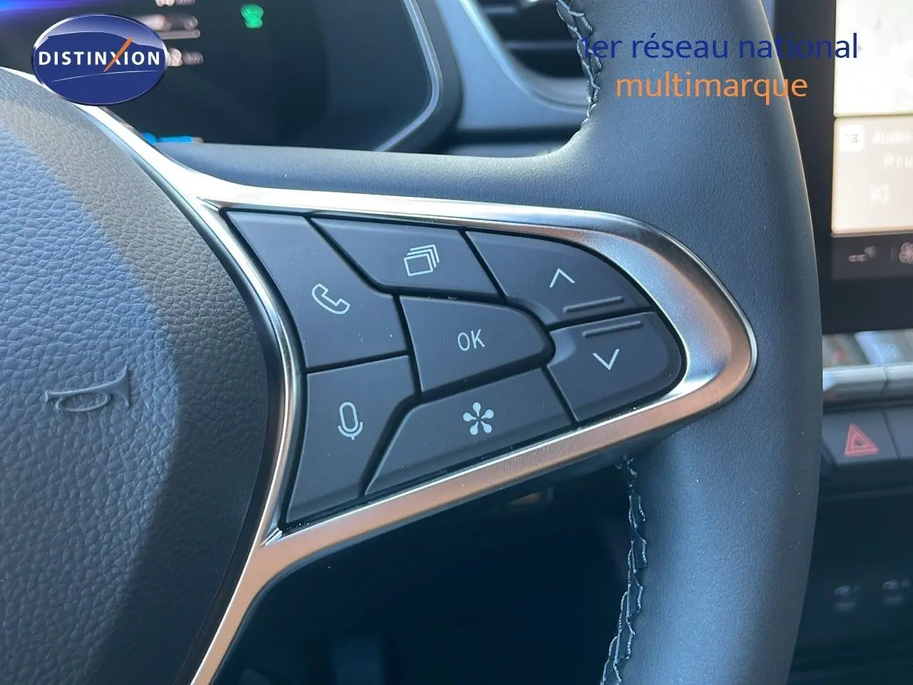 Gros plan sur les commandes multifonctions côté gauche du volant d’un Renault Captur blanc nacré 2025 hybride.