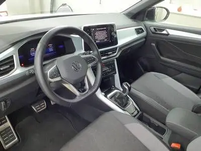 Vue intérieure côté conducteur du Volkswagen T-Roc 2025, tableau de bord moderne avec écran central et volant multifonction.