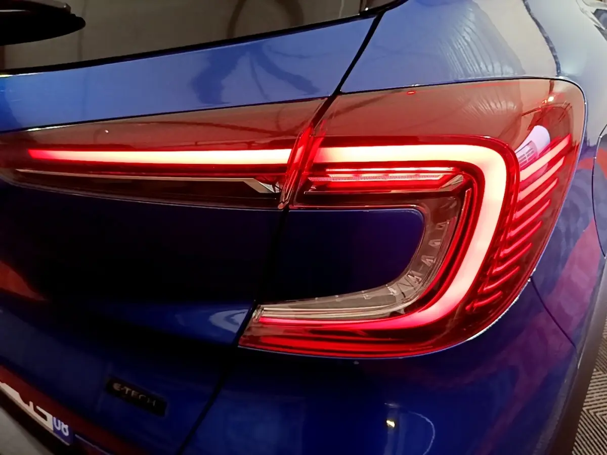 Gros plan sur le feu arrière droit rouge allumé du Renault Captur bleu E-Tech full hybrid 145 de 2023.