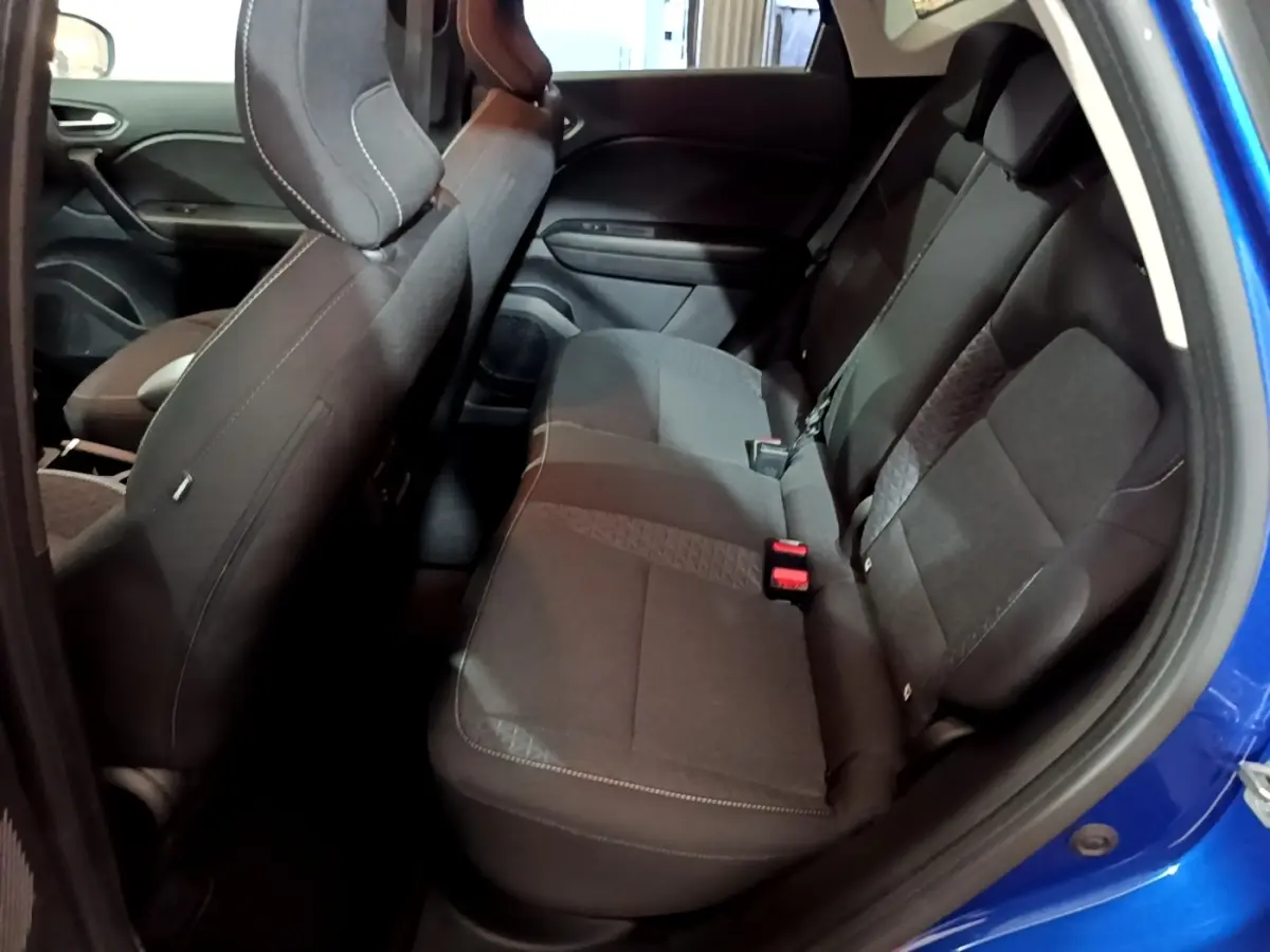 Vue intérieure côté droit des sièges arrière noirs du Renault Captur bleu 2023, banquette 3 places avec ceintures visibles.