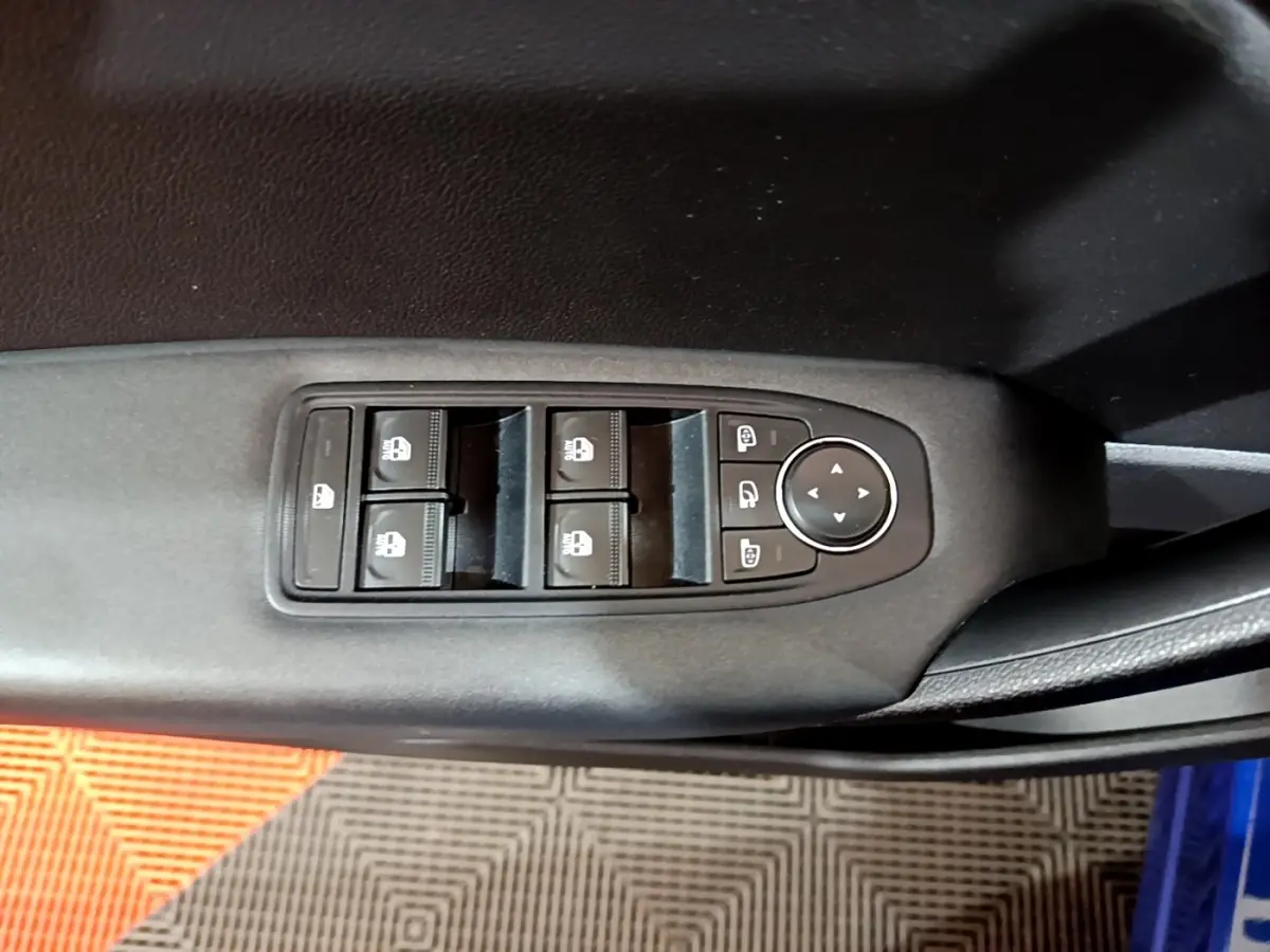 Vue rapprochée des commandes de lève-vitres et réglages des rétroviseurs sur la porte côté conducteur d’un Renault Captur bleu.