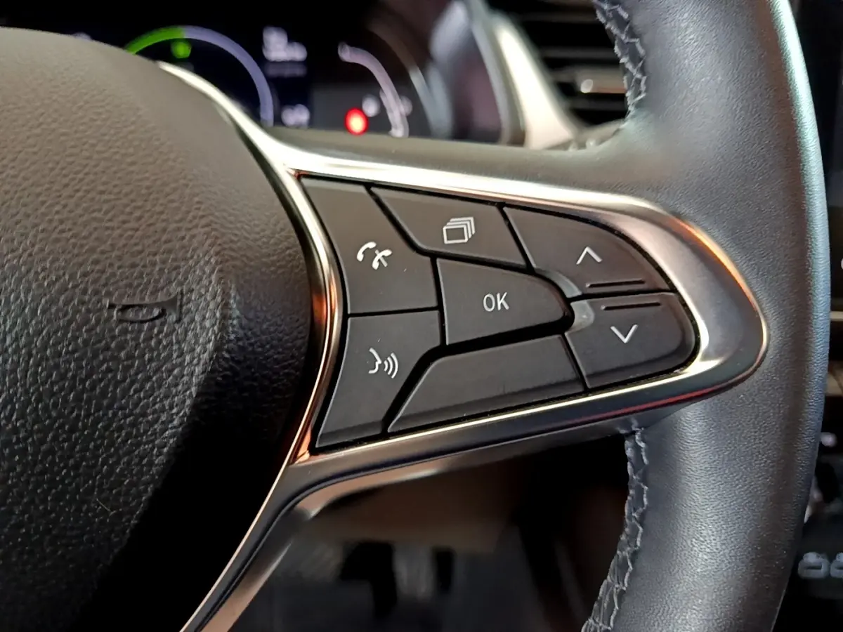 Gros plan sur les commandes multifonctions à droite du volant cuir noir du Renault Captur bleu hybride 2023.