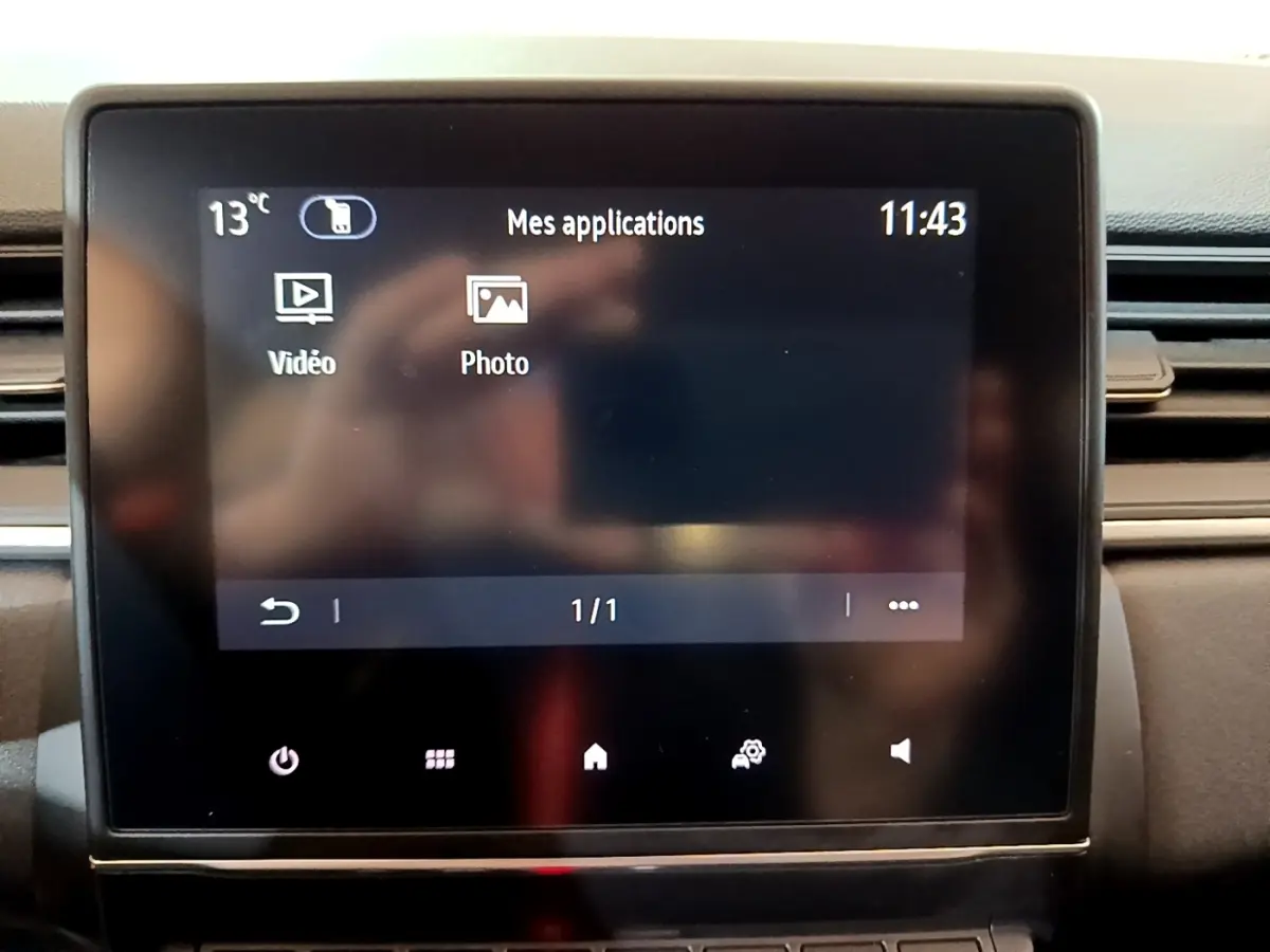 Écran tactile central du tableau de bord du Renault Captur bleu, affichant les applications vidéo et photo.
