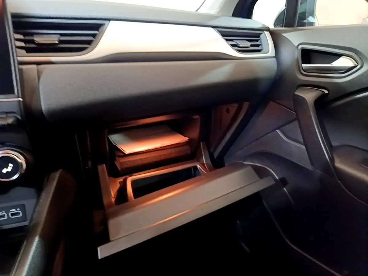 Intérieur Renault Captur 2023, vue côté passager sur boîte à gants ouverte avec éclairage intérieur chaud.