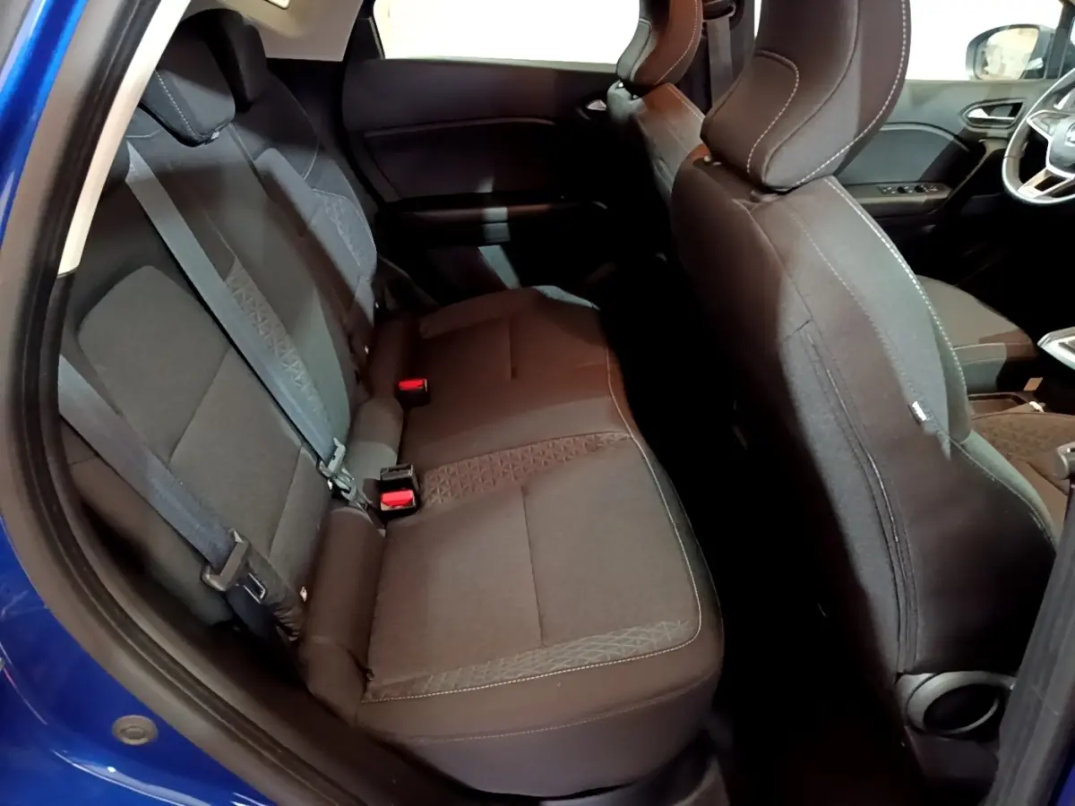 Vue intérieure côté arrière gauche du Renault Captur bleu, montrant la banquette arrière en tissu noir avec ceintures de sécurité.
