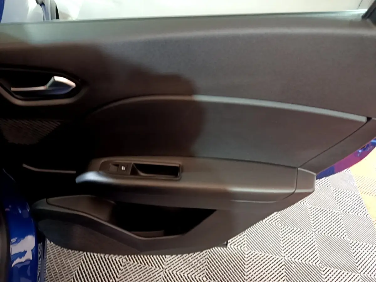 Vue intérieure du panneau de porte avant gauche du Renault Captur bleu, avec commande de fenêtre et poignée intégrée.