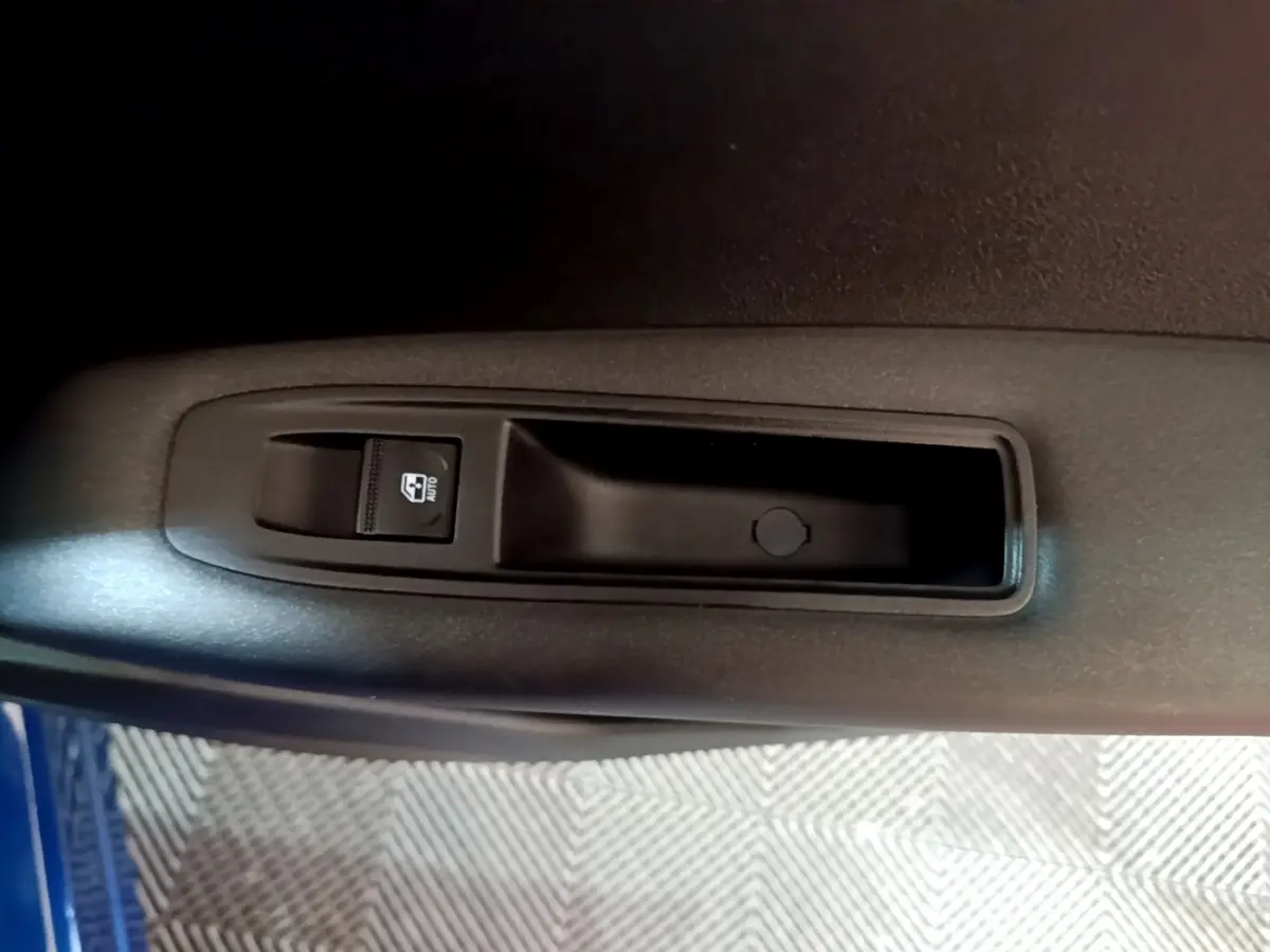 Gros plan sur la commande de lève-vitre côté conducteur dans l’habitacle du Renault Captur bleu 2023.