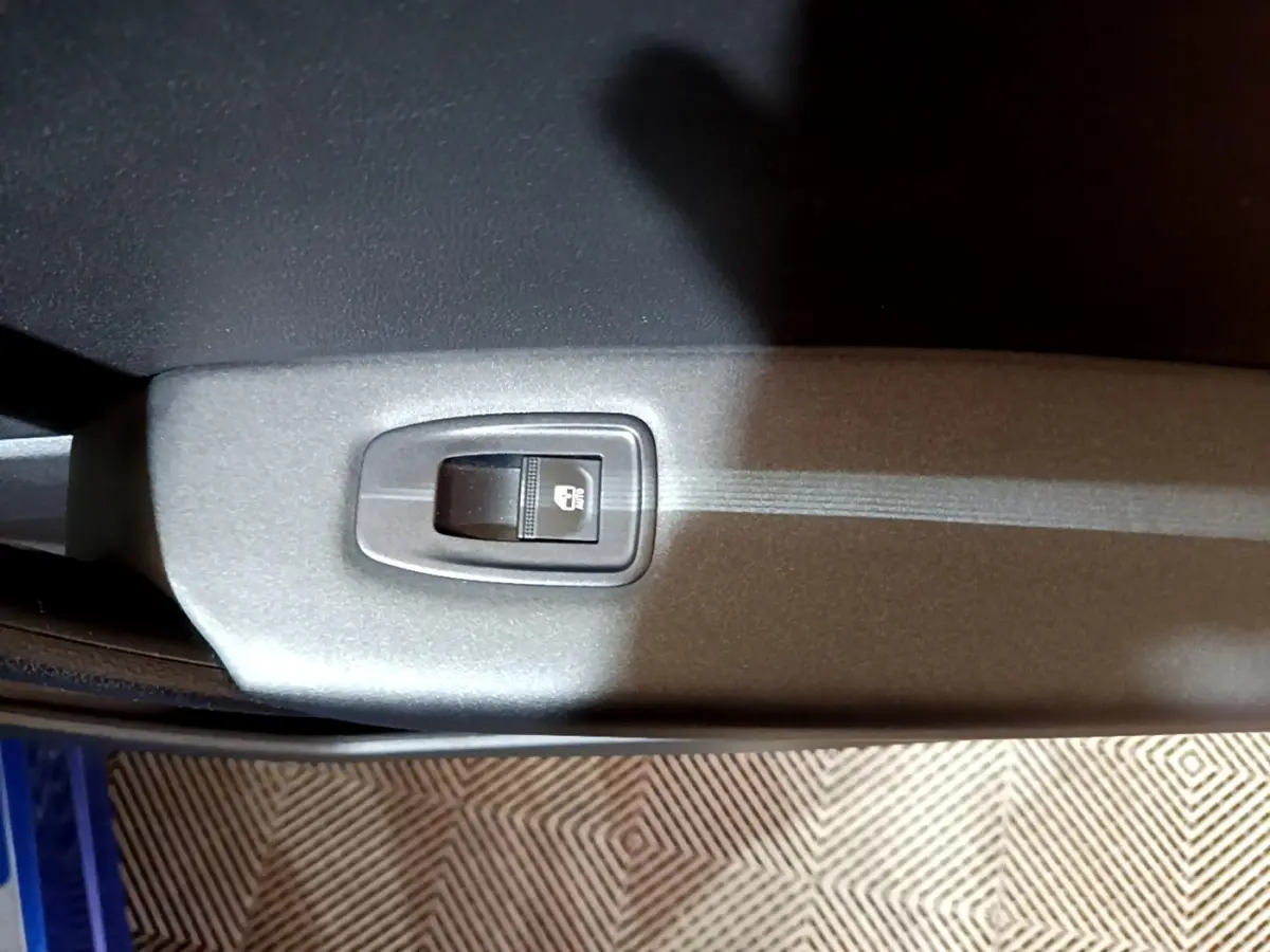 Gros plan sur le bouton de verrouillage des portes dans l'habitacle du Renault Captur bleu, côté intérieur de porte.