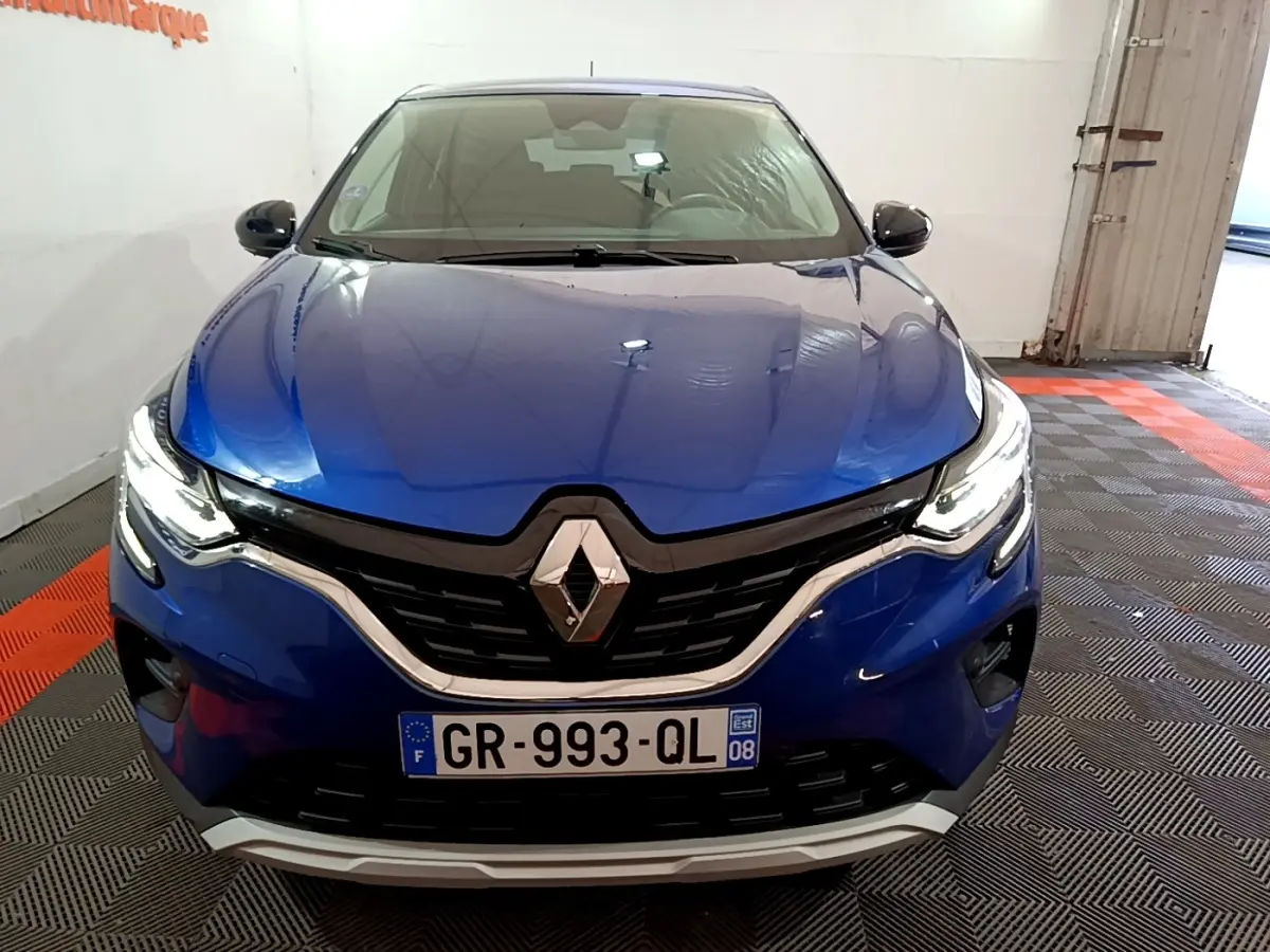 Vue avant d'un Renault Captur bleu 2023 avec phares LED allumés et calandre noire chromée.