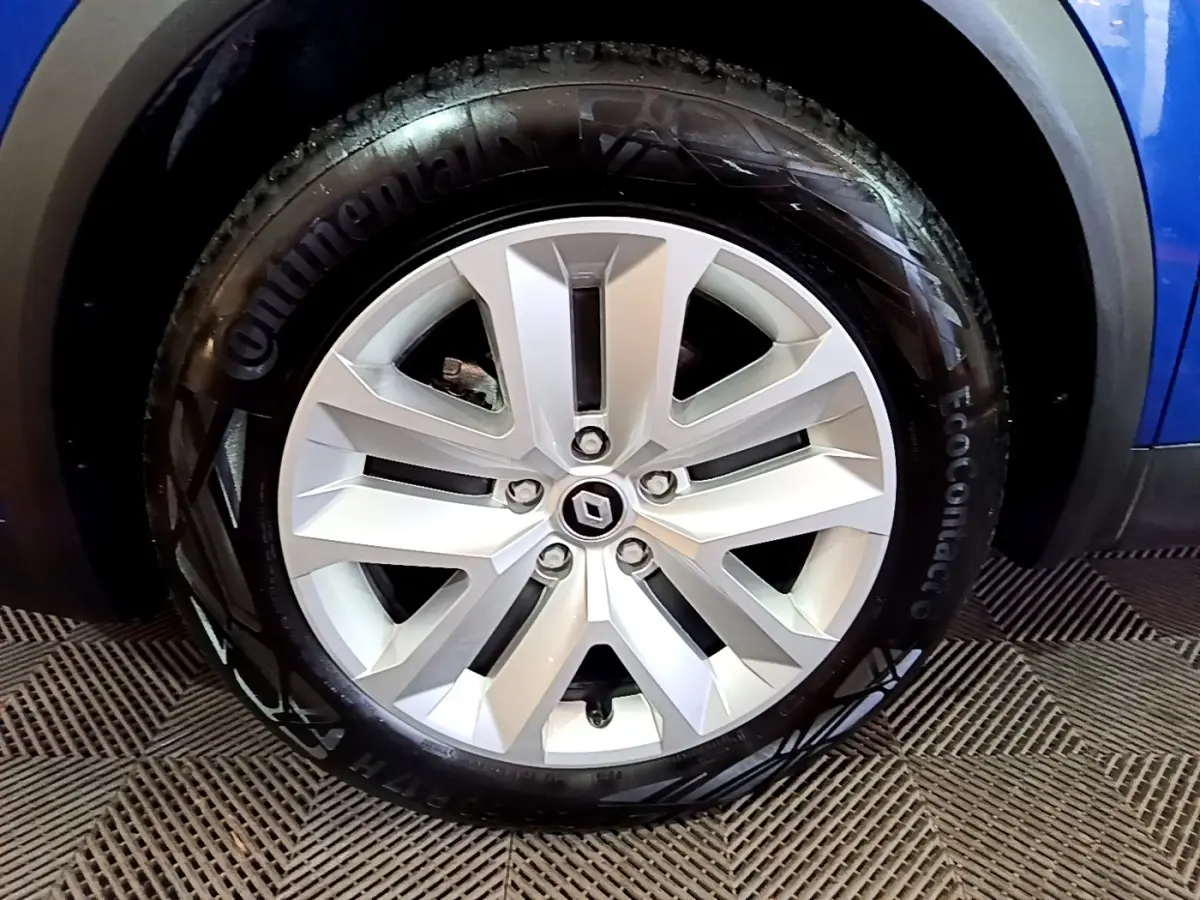 Vue rapprochée de la roue arrière droite d’un Renault Captur bleu 2023 avec jante alliage et passage de roue noir.