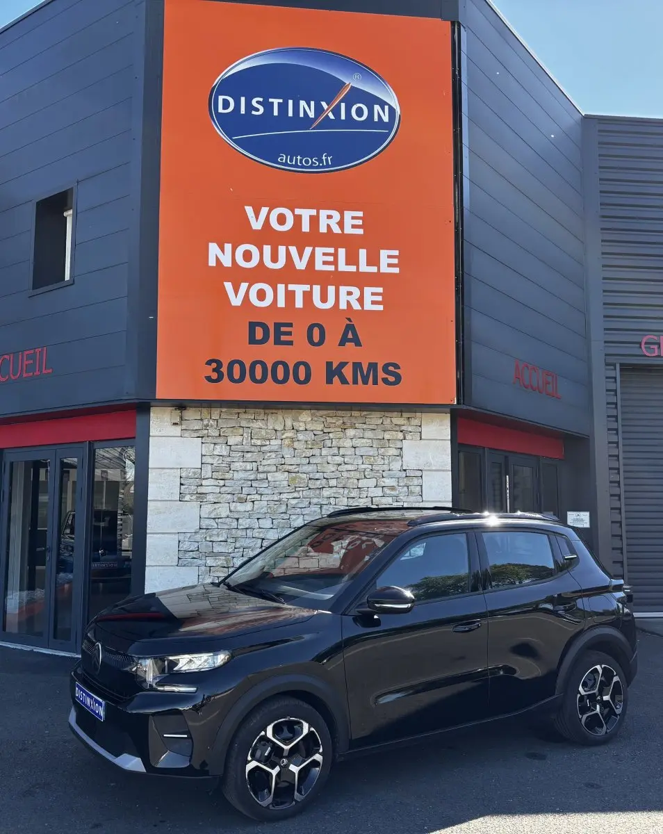 Citroën C3 noire vue en 3/4 avant droit, avec jantes 16 pouces et toit avec rails noirs devant un bâtiment commercial.