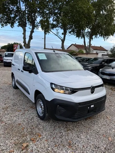 Citroën Berlingo Van blanc vu en 3/4 avant droit sur un parking, avec calandre noire et feux allumés.