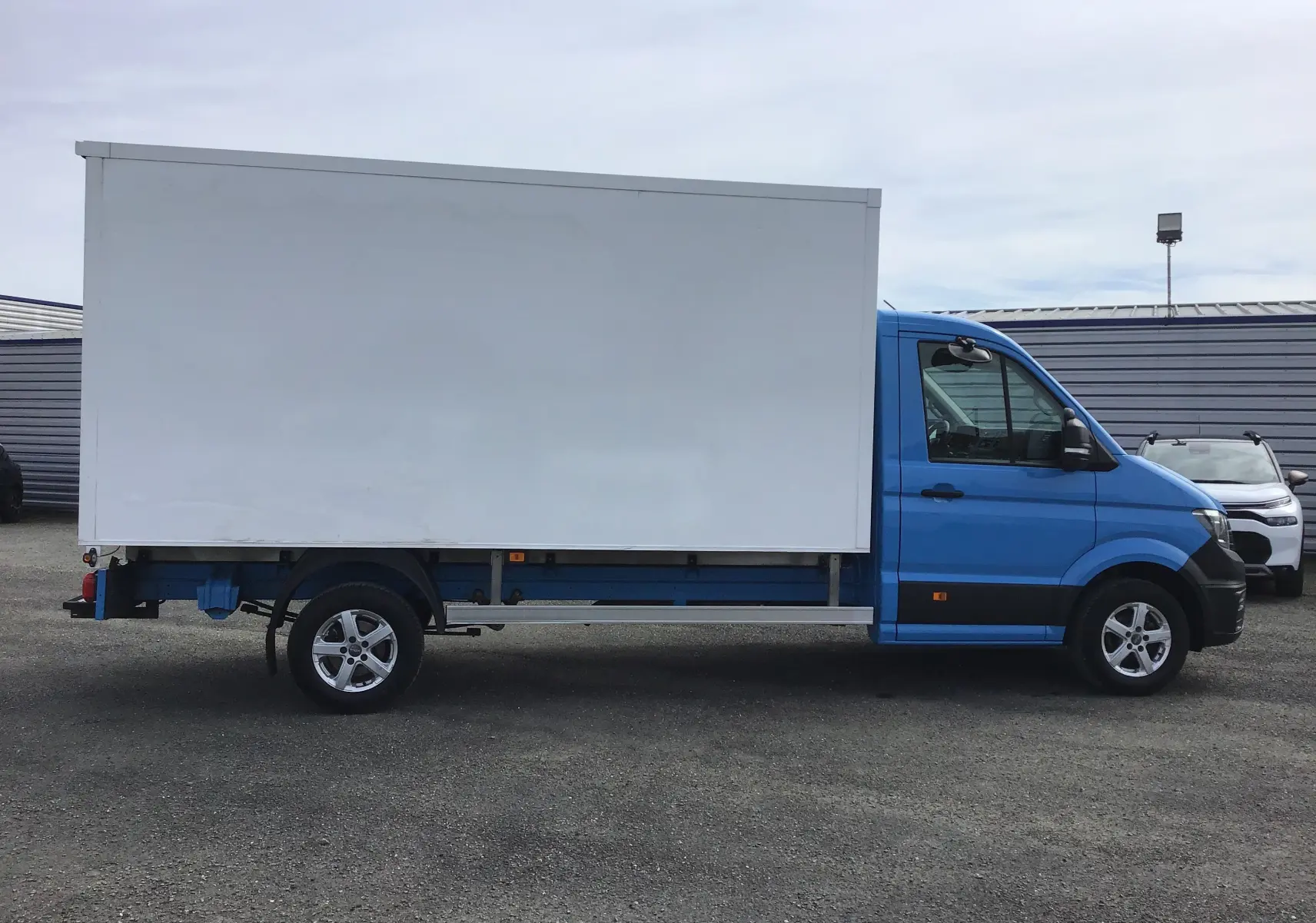 Profil latéral droit d'un Volkswagen Crafter Chassis Cabine bleu de 2017 avec caisse blanche et jantes alu 16 pouces.