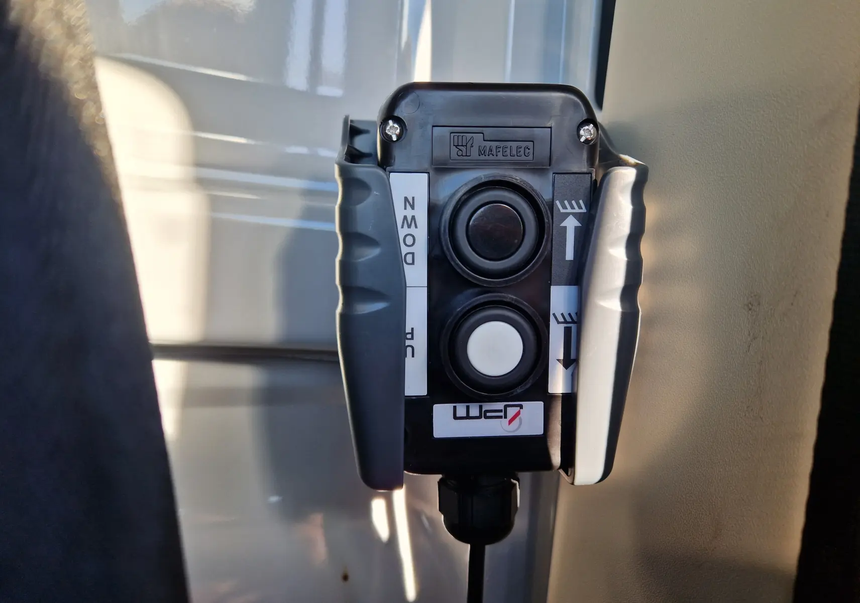 Gros plan sur commande Mafelec noire avec deux boutons pour benne, à l'intérieur d'un Fiat Ducato blanc 2023.