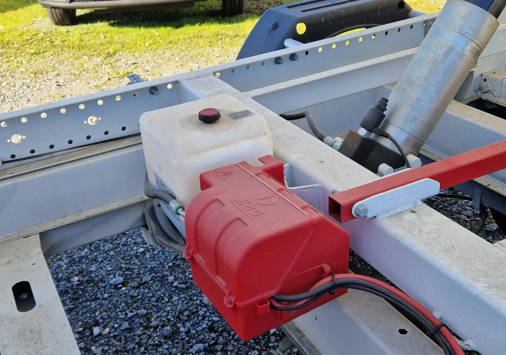 Détail du châssis blanc du Fiat Ducato benne 2023, avec coffre rouge JPM et réservoir plastique vue de côté droit.