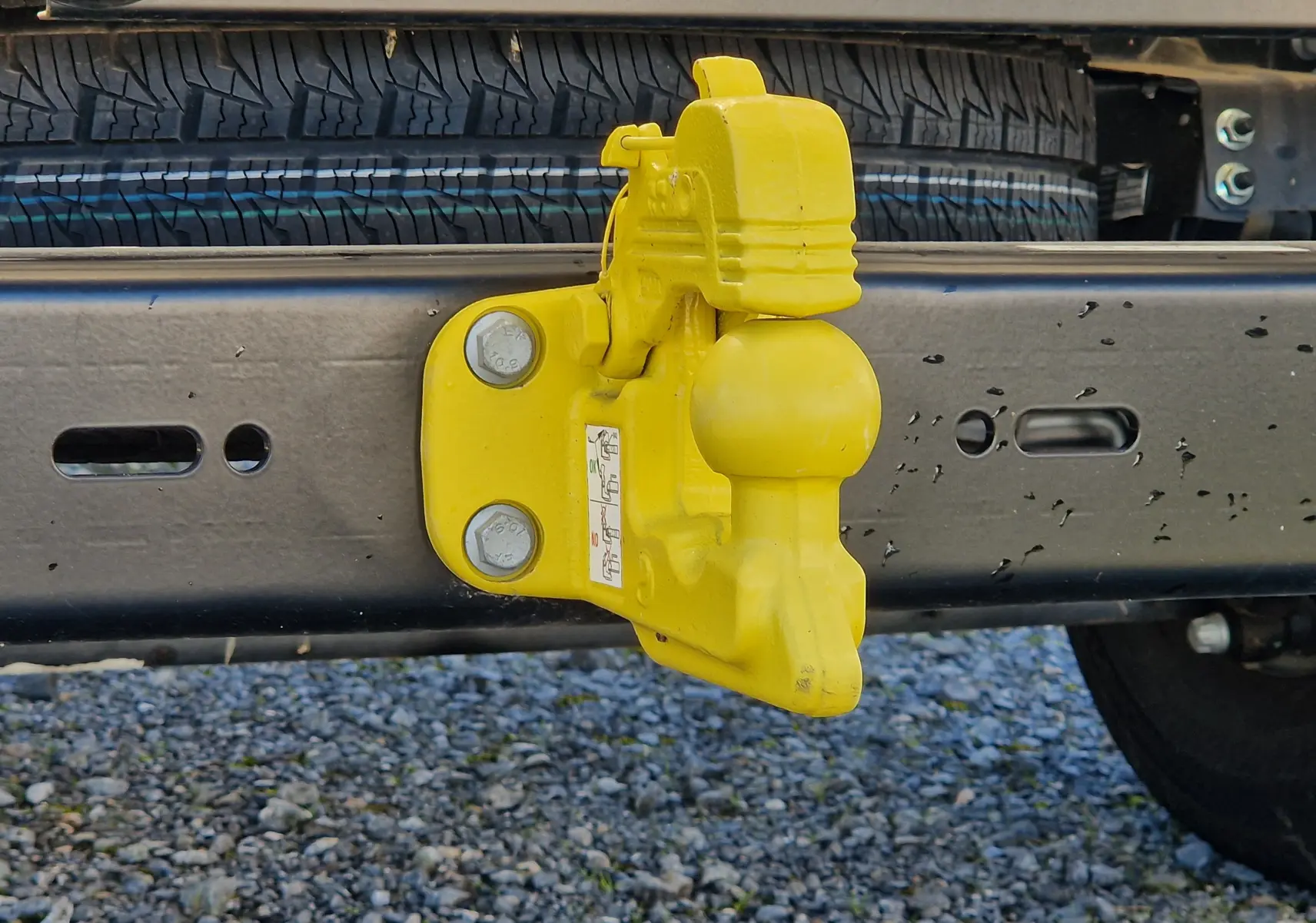 Gros plan sur l'attelage jaune fixé au châssis arrière du FIAT Ducato Chassis Benne blanc 2023.