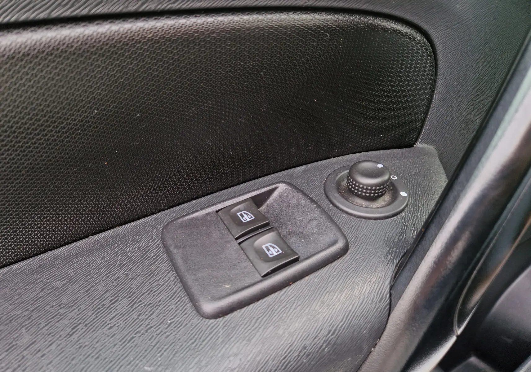 Gros plan sur les commandes électriques des vitres et le réglage des rétroviseurs côté conducteur du Renault Kangoo blanc 2020.