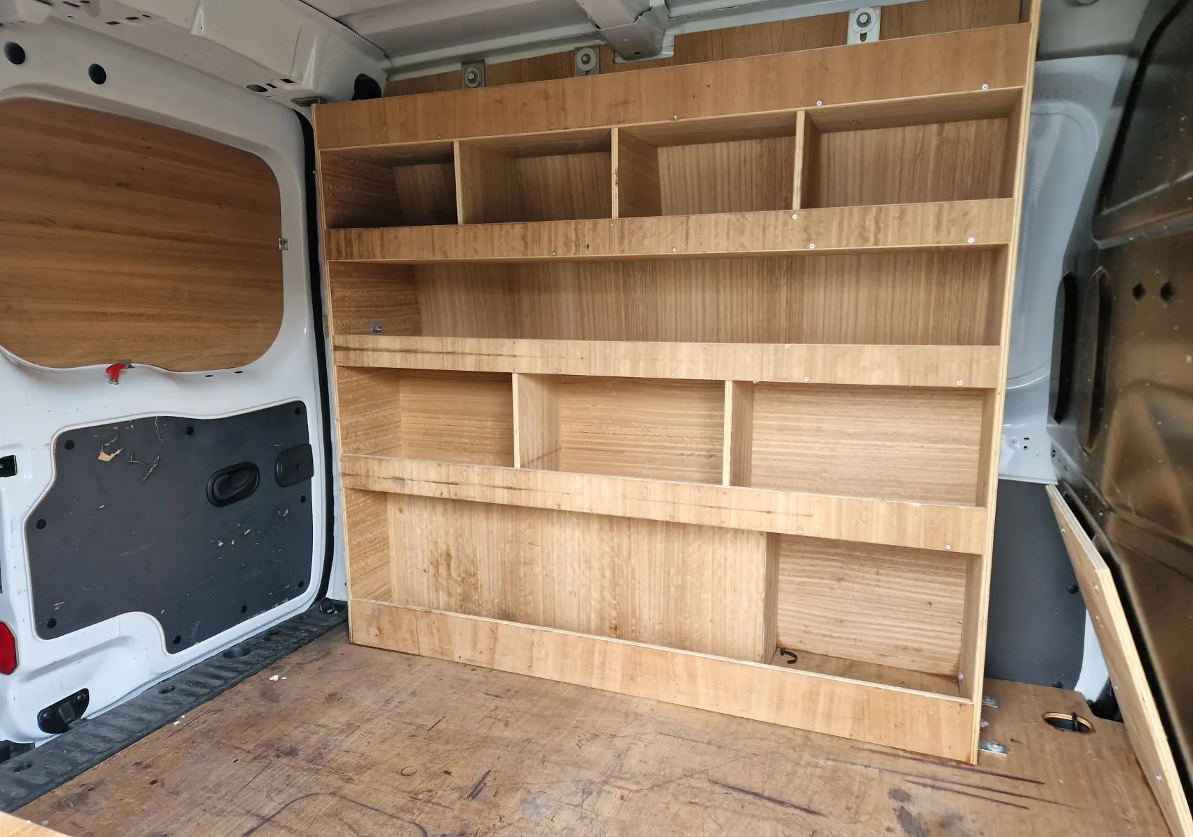 Vue intérieure arrière du Renault Kangoo blanc 2020, montrant les étagères en bois intégrées au compartiment de chargement.