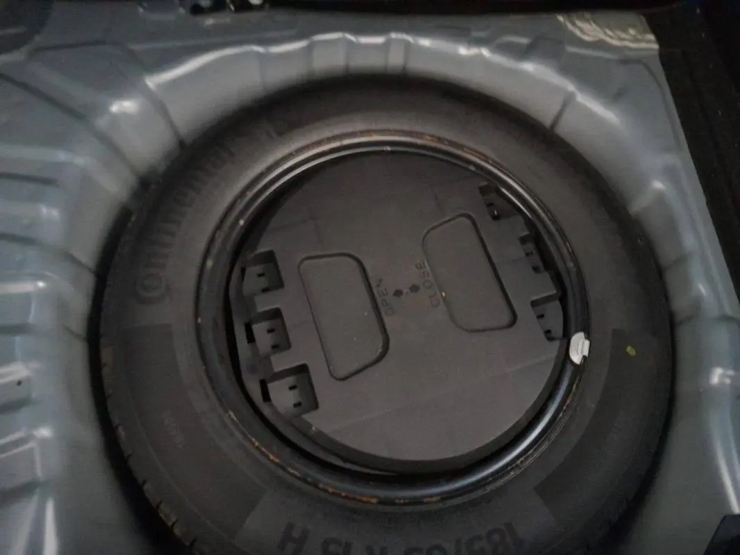 Gros plan sur la roue de secours noire dans le coffre d'une Renault Clio gris foncé, version V TCe 100 Business 2019.