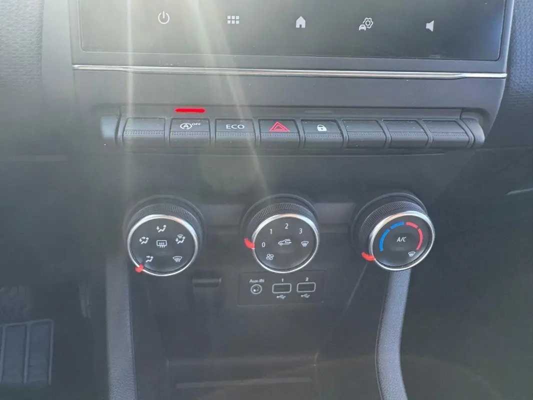 Vue rapprochée du tableau de bord de la Renault Clio 2019 gris foncé, montrant les commandes de climatisation et boutons fonctionnels.