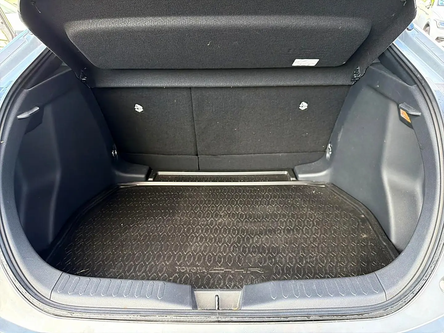 Coffre ouvert d’un Toyota C-HR gris, vue arrière montrant la surface de chargement avec tapis de protection noir.
