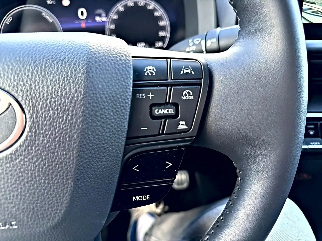 Gros plan sur le volant multifonction noir du Toyota C-HR 1.8 hybride 2025 avec commandes de régulateur et assistance.