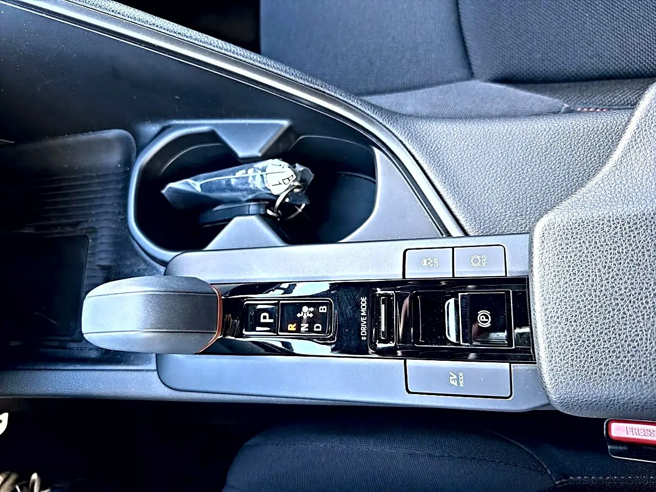 Vue rapprochée de la console centrale du Toyota C-HR gris, avec levier de vitesse automatique et accoudoir.