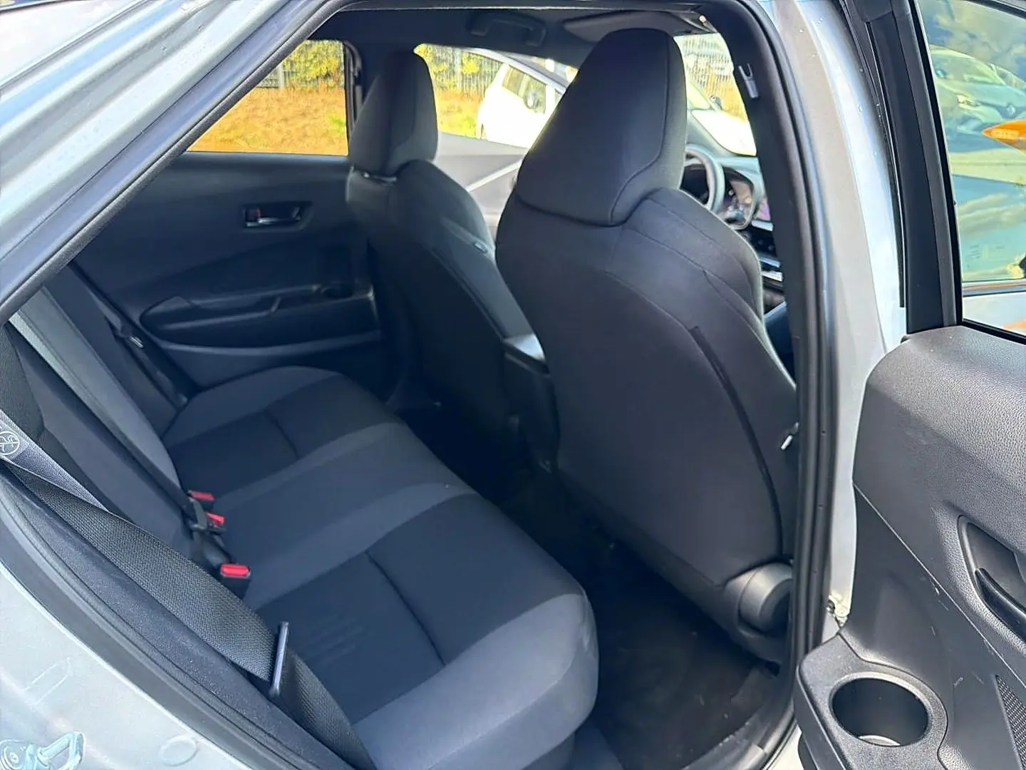 Vue intérieure côté gauche sur la banquette arrière et sièges avant noirs du Toyota C-HR gris 2025 hybride.