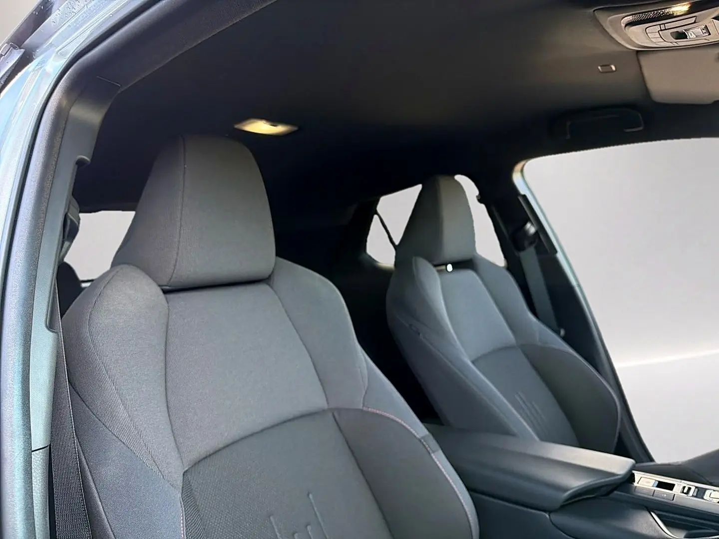 Vue intérieure sur les sièges avant gris foncé du Toyota C-HR 1.8 hybride 2025 avec accoudoir central.