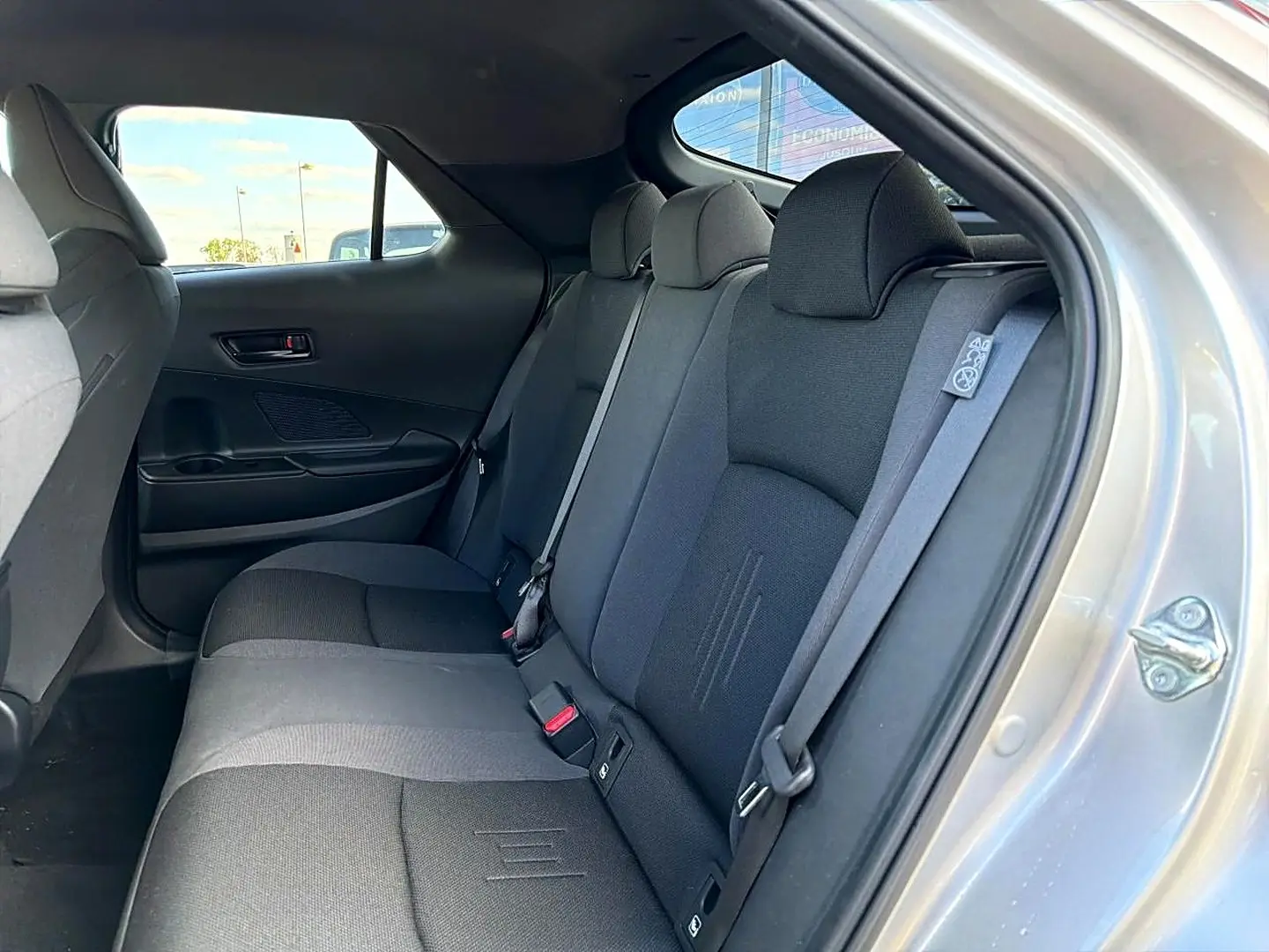 Vue intérieure côté droit sur la banquette arrière grise du Toyota C-HR 1.8 hybride 2025 avec ceinture de sécurité visible.