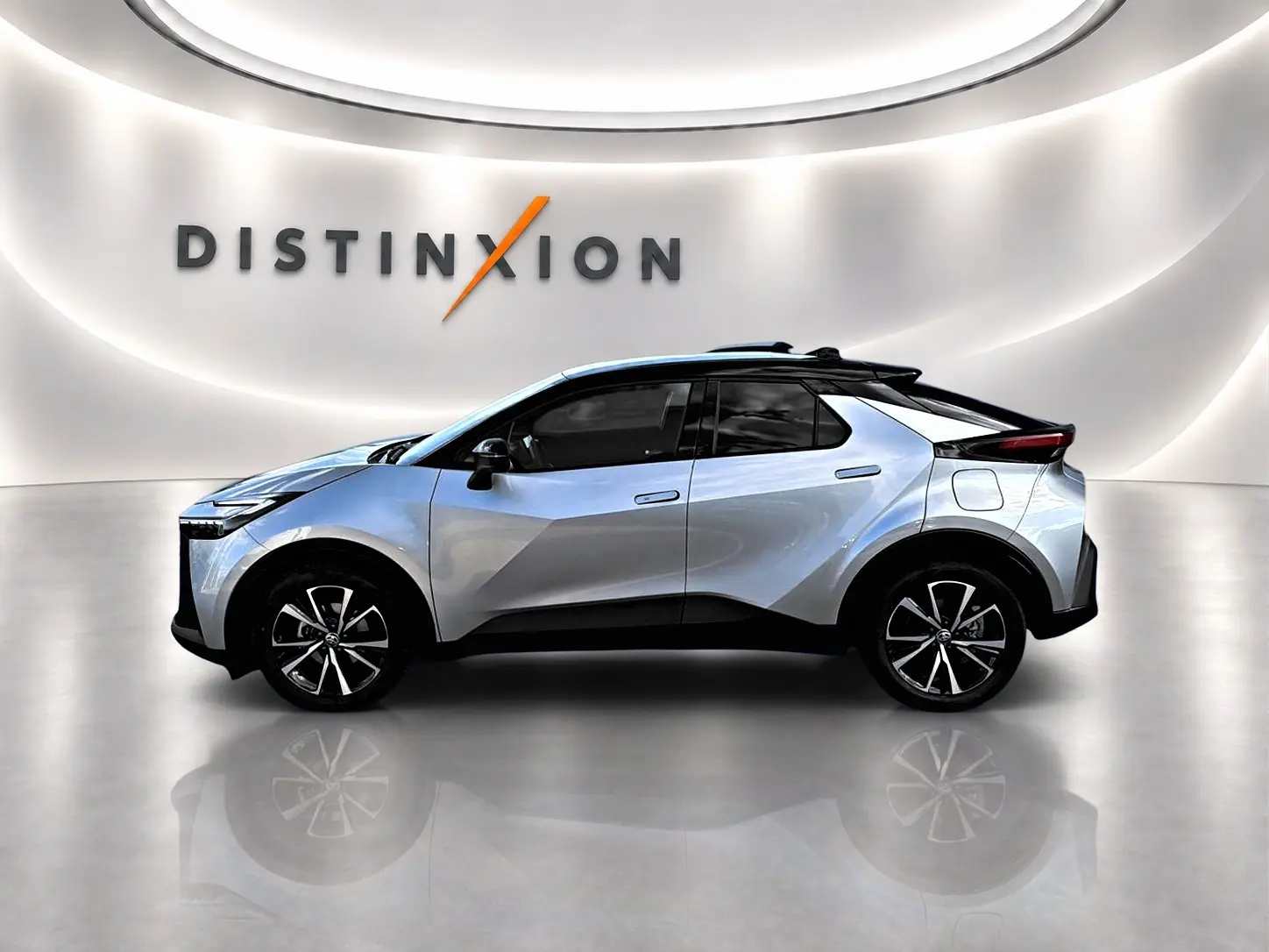 Profil côté gauche d'un Toyota C-HR gris 2025 avec jantes alliage et toit noir dans un showroom lumineux.