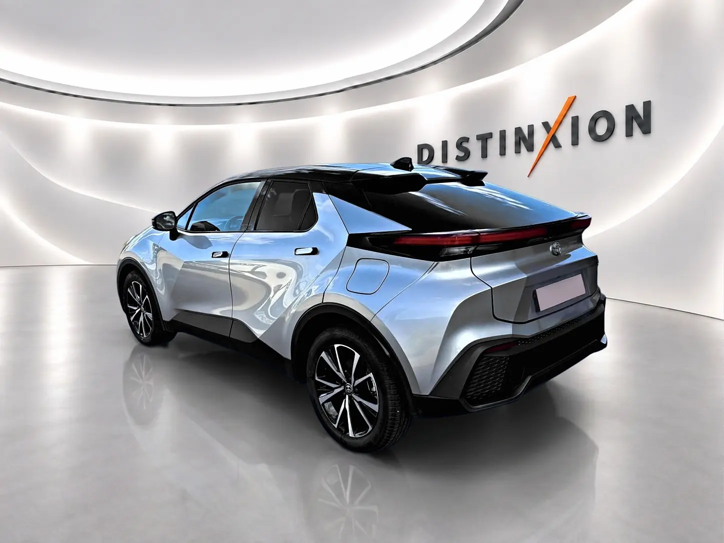 Toyota C-HR 1.8 hybride gris en 3/4 arrière droit, avec toit noir et feux arrière LED fins.