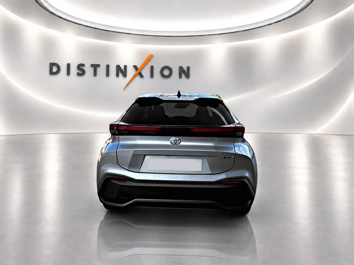 Vue arrière d'un Toyota C-HR 1.8 hybride gris 2025 dans un showroom avec logo Distinxion en arrière-plan.