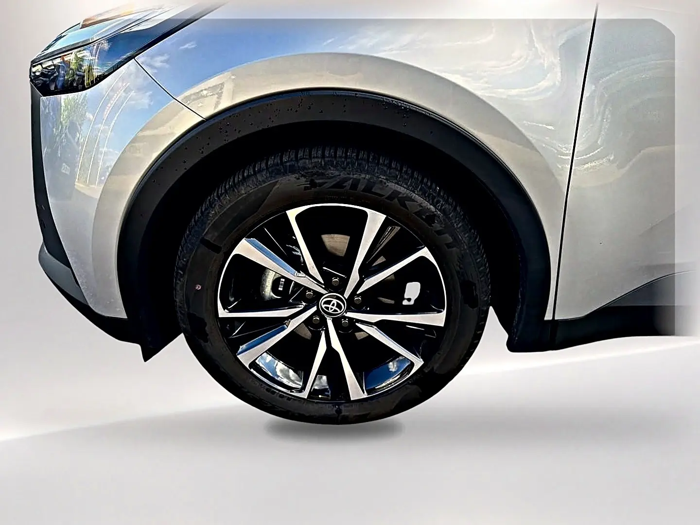 Gros plan sur la roue avant gauche du Toyota C-HR 1.8 hybride gris avec jante alliage noir et argent.