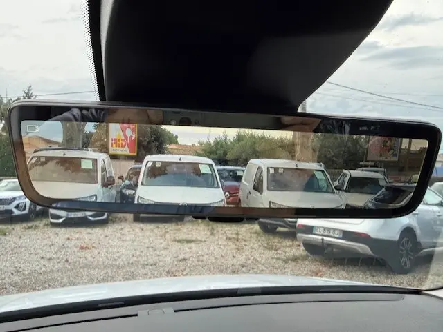 Vue arrière dans le rétroviseur intérieur d'un Citroën Berlingo blanc 2026, version van diesel, sur un parking.
