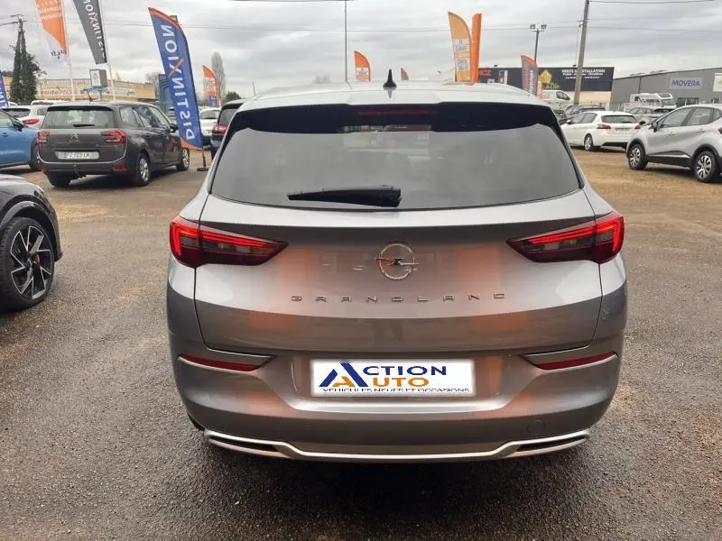 Vue arrière d'un Opel Grandland gris Kontrast métallisé 2023, avec feux LED et logo central sur un parking.