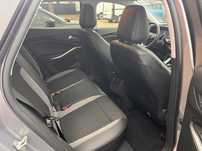 Vue intérieure côté arrière droit de l’Opel Grandland gris Kontrast, sièges tissu noir et gris avec détails en cuir.
