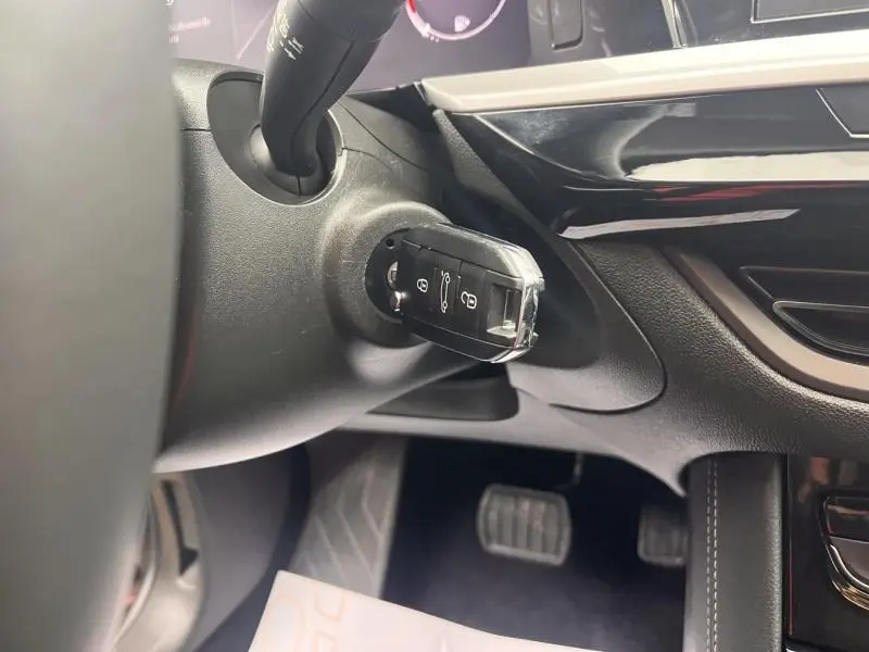 Gros plan sur la clé insérée dans le contacteur du tableau de bord noir brillant de l’Opel Grandland gris Kontrast.