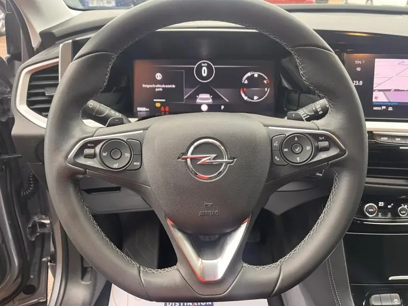 Vue intérieure centrée sur le volant cuir multifonction de l'Opel Grandland 2023 avec tableau de bord et écran tactile visibles.