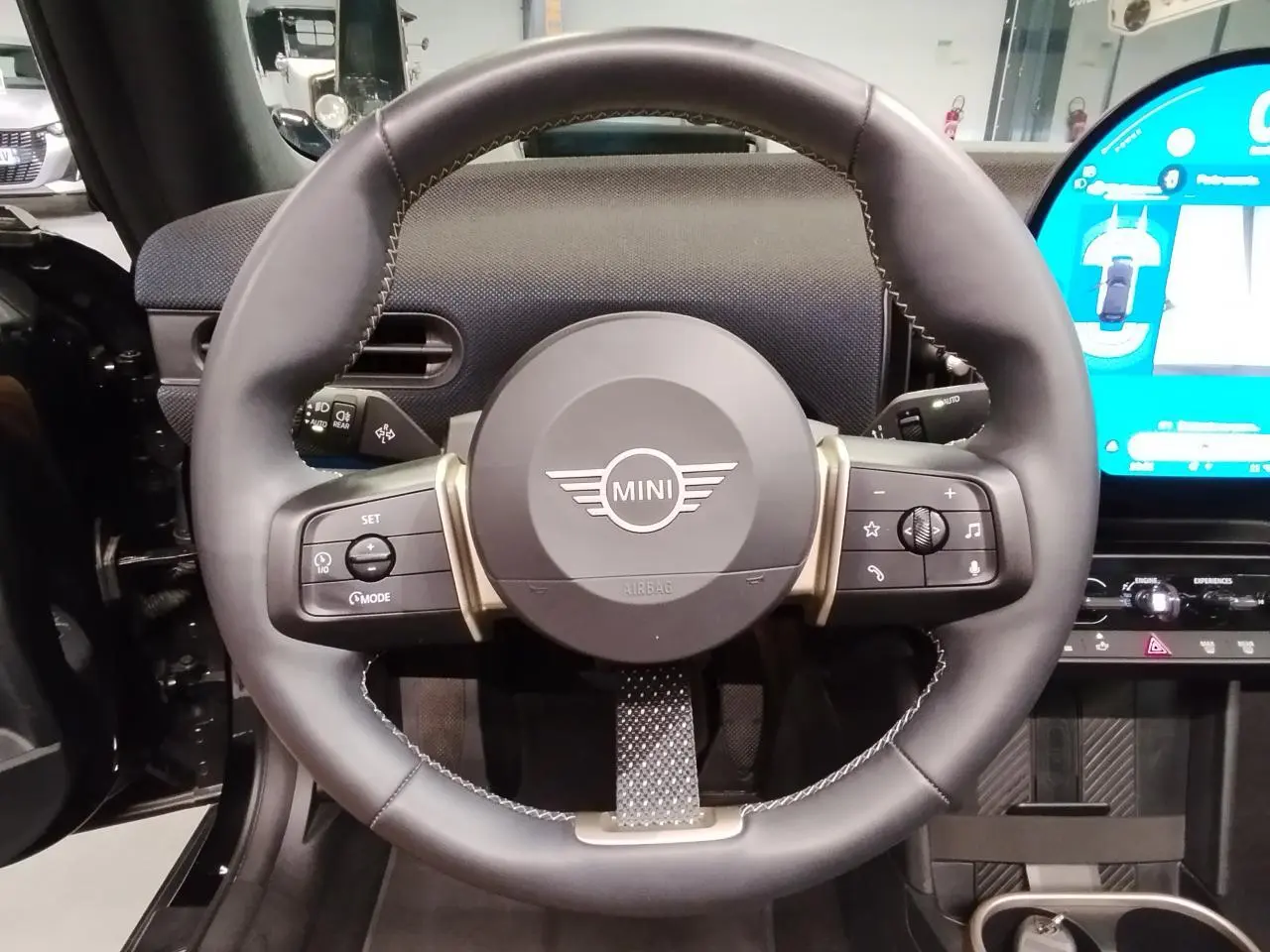 Volant cuir noir multifonction de la MINI Cabriolet 2025 avec tableau de bord et écran tactile visible à droite.