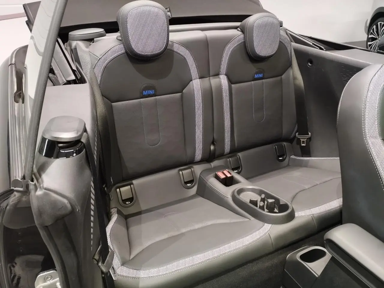 Vue intérieure arrière du cabriolet MINI noir, sièges arrière en similicuir perforé avec logo MINI bleu.