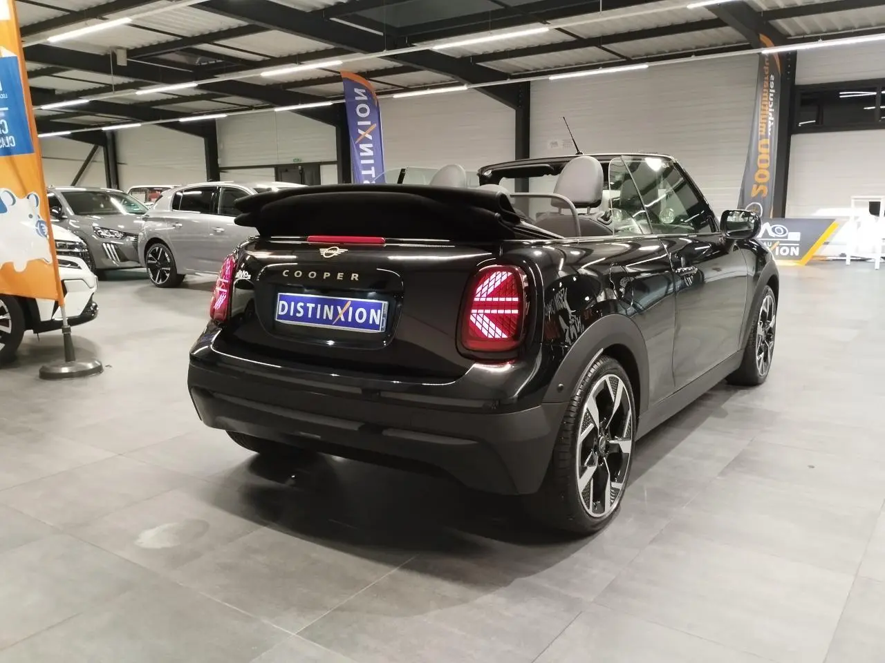 Vue 3/4 arrière droite d'une MINI Cabriolet noire avec capote souple repliée et feux arrière à LED Union Jack.