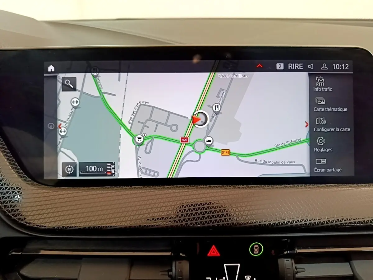 Écran tactile central de navigation 3D affichant une carte routière dans une BMW Série 1 bleue, vue intérieure.