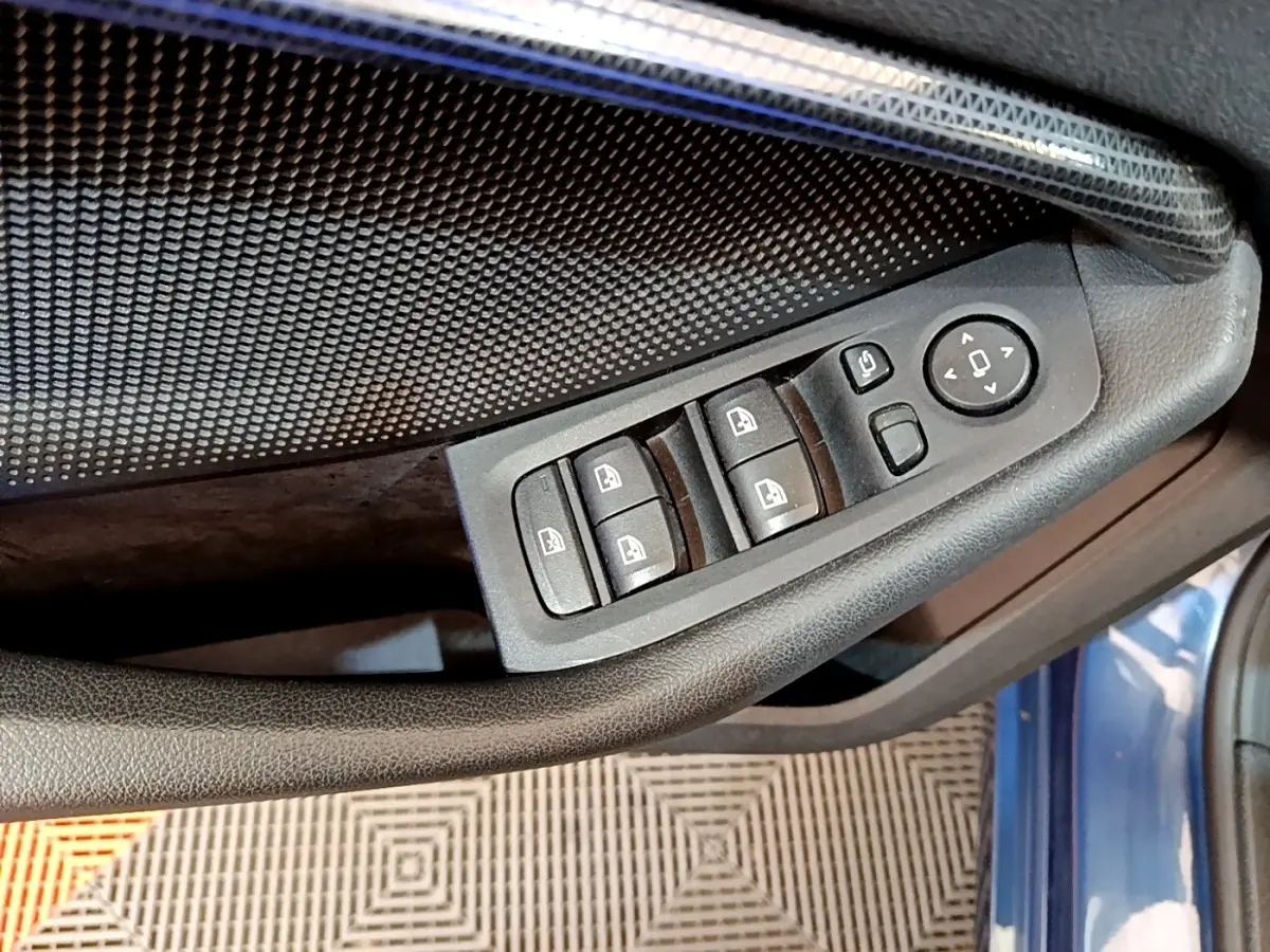 Détail des commandes des vitres et rétroviseurs sur la porte côté gauche d’une BMW Série 1 bleu 2023.