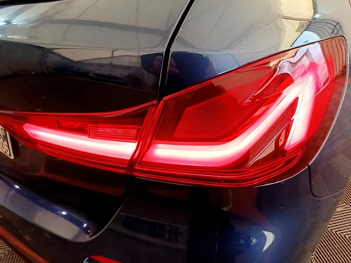 Gros plan sur le feu arrière droit rouge allumé d’une BMW Série 1 118i Edition Sport bleu 2023.